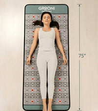 Woman lying on a Grooni PEMF mat with dimensions indicated.