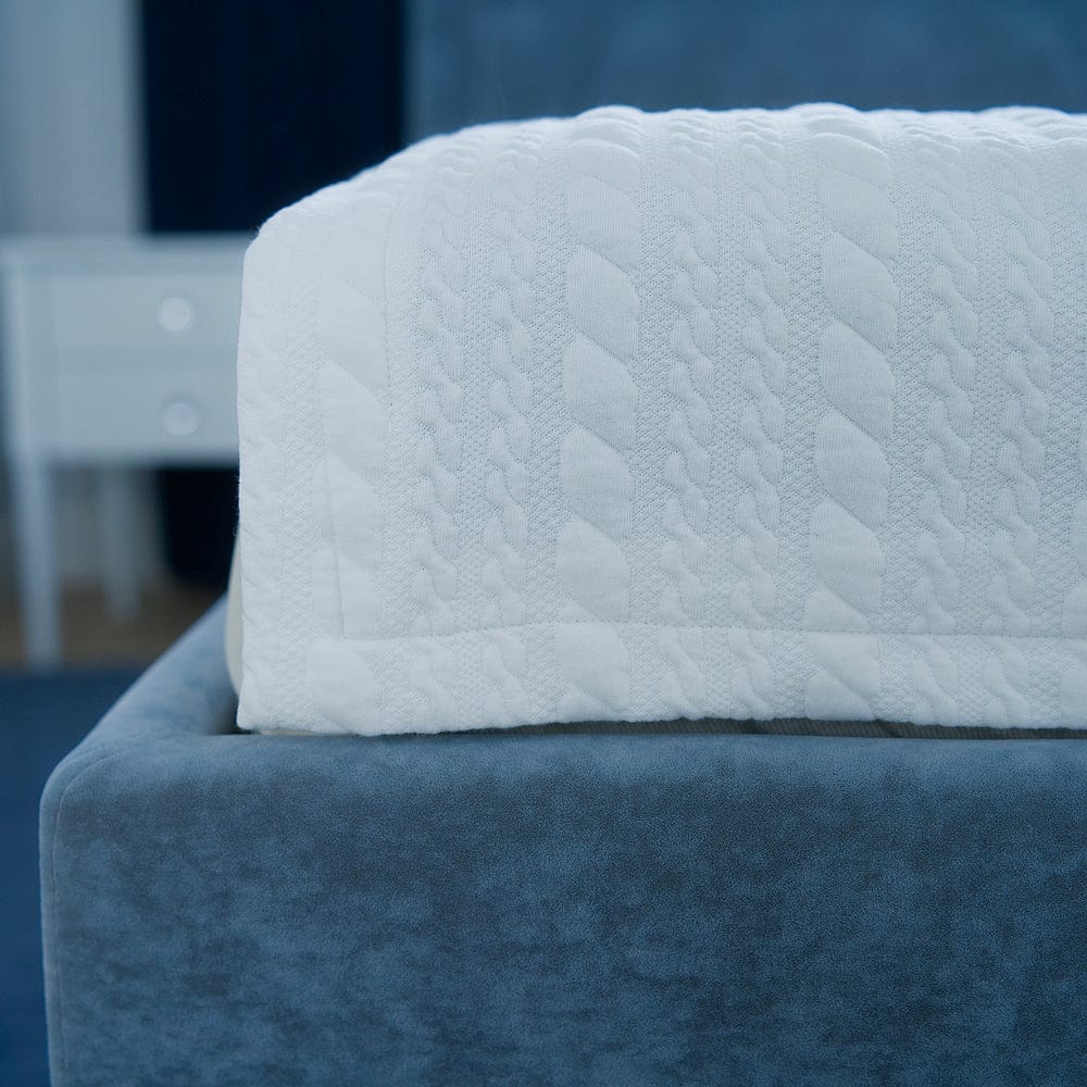 White quilted grounding blanket on a blue bed frame with a blurred background