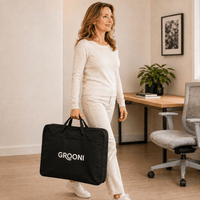 A woman in a cream sweater and pants carries a black duffel bag with the brand name 'GROONI' printed in white, walking in a bright, modern home office.
