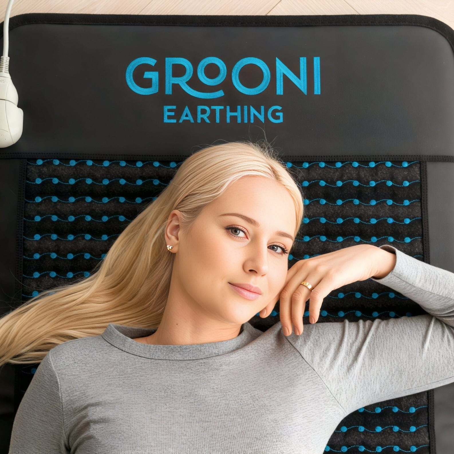 Woman laying over a PEMF Infrared mat looking relaxed and looking directly into the camera