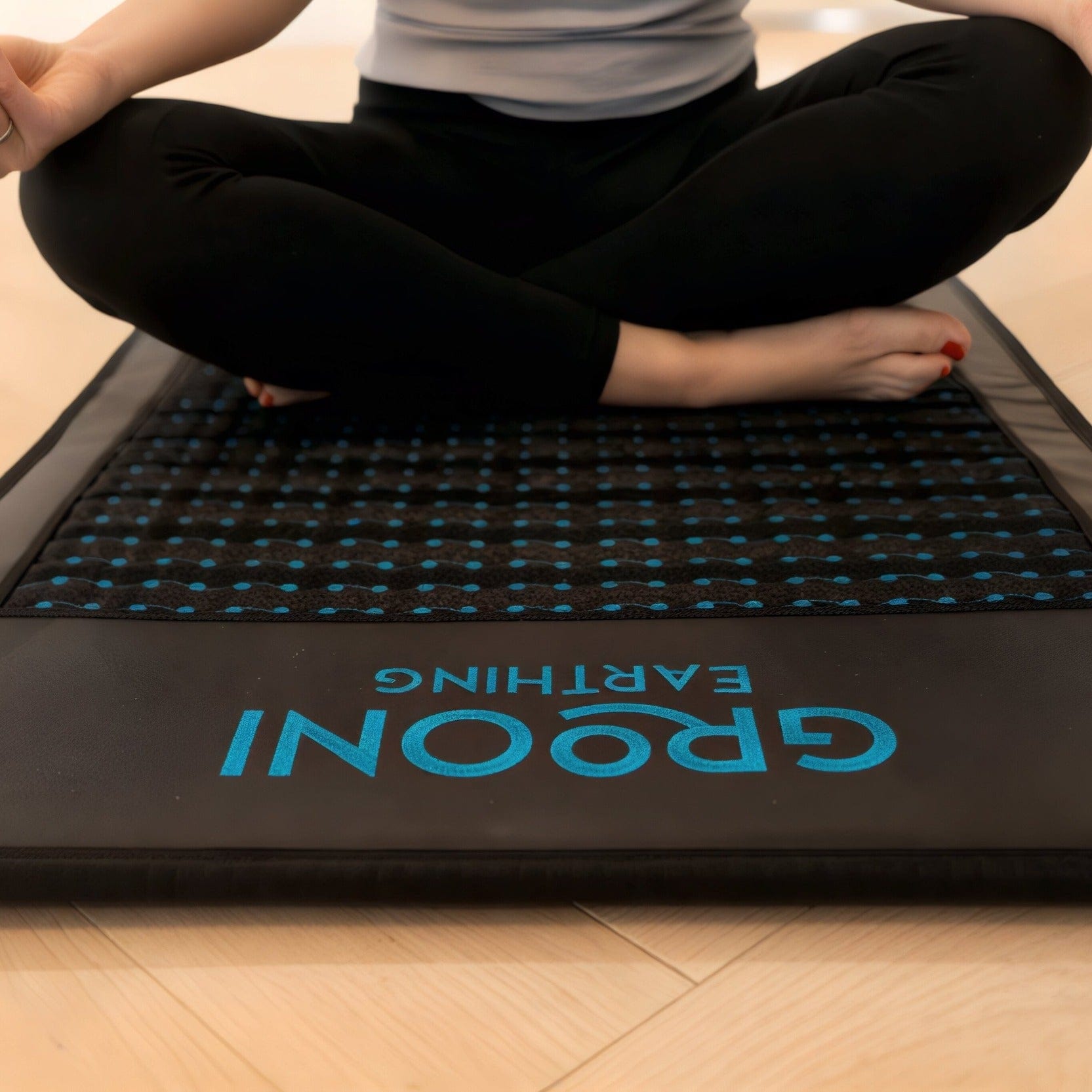Woman over a PEMF Infrared Mat in a lotus pose.