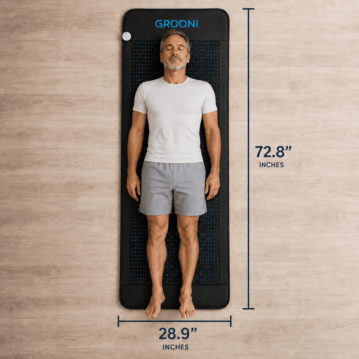 A man lies flat on a long, narrow black mat with measurement lines and text showing dimensions: 72.8 inches tall and 28.
