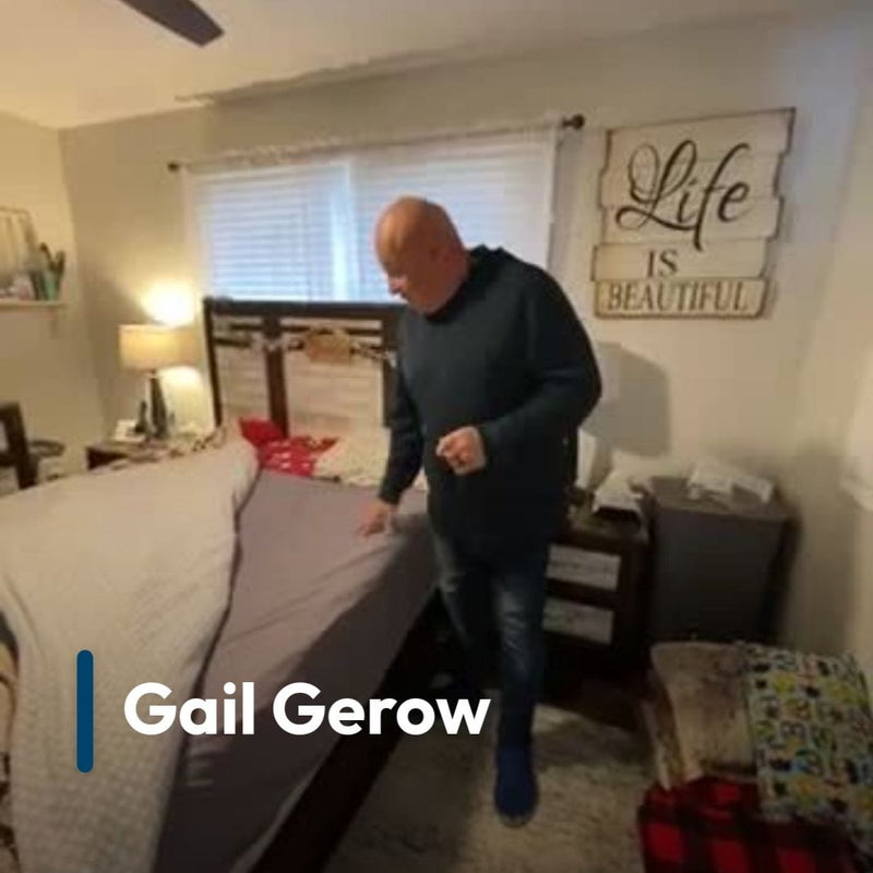 Man adjusting a mattress in a bedroom with 'Life is Beautiful' decor.